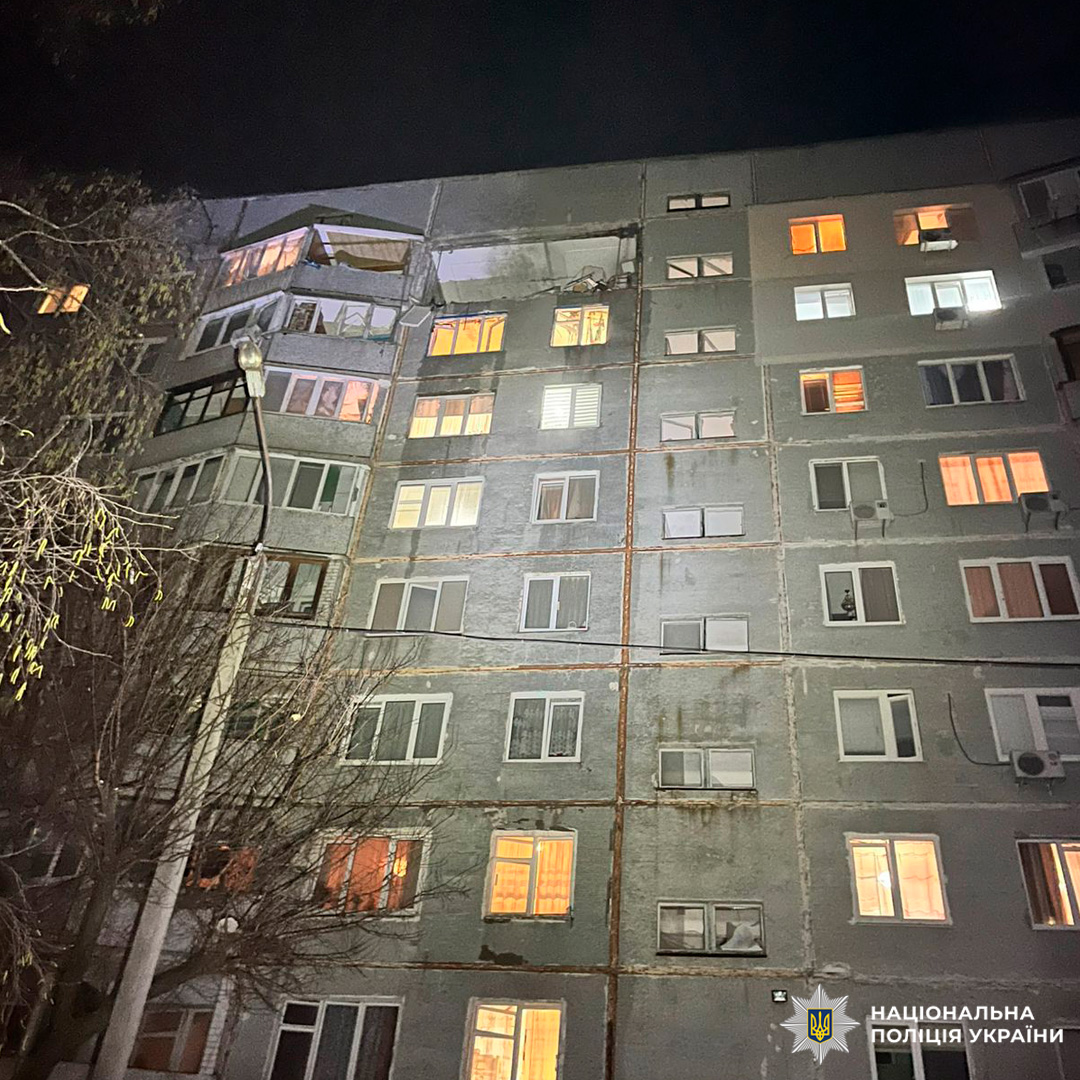 Багатоповерховий житловий будинок уночі з пошкодженими верхніми поверхами.