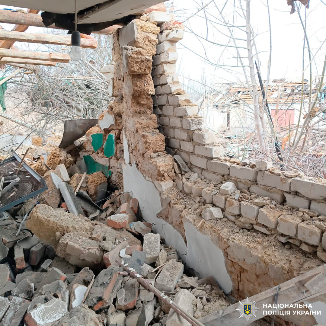 Зруйнована цегляно-глиняна стіна будинку з уламками та відкритим інтер’єром.