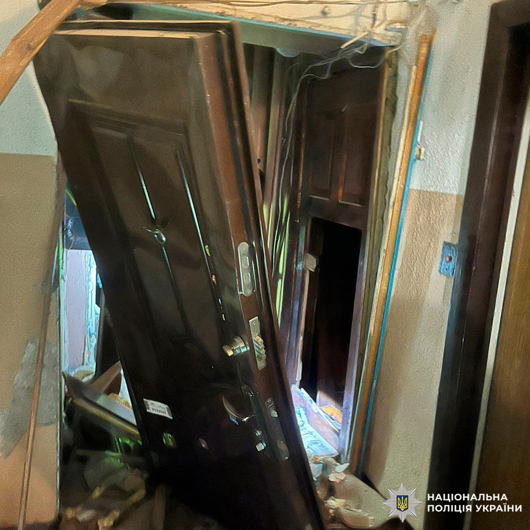 Пошкоджений дверний проріз із деформованими дверима та уламками.
