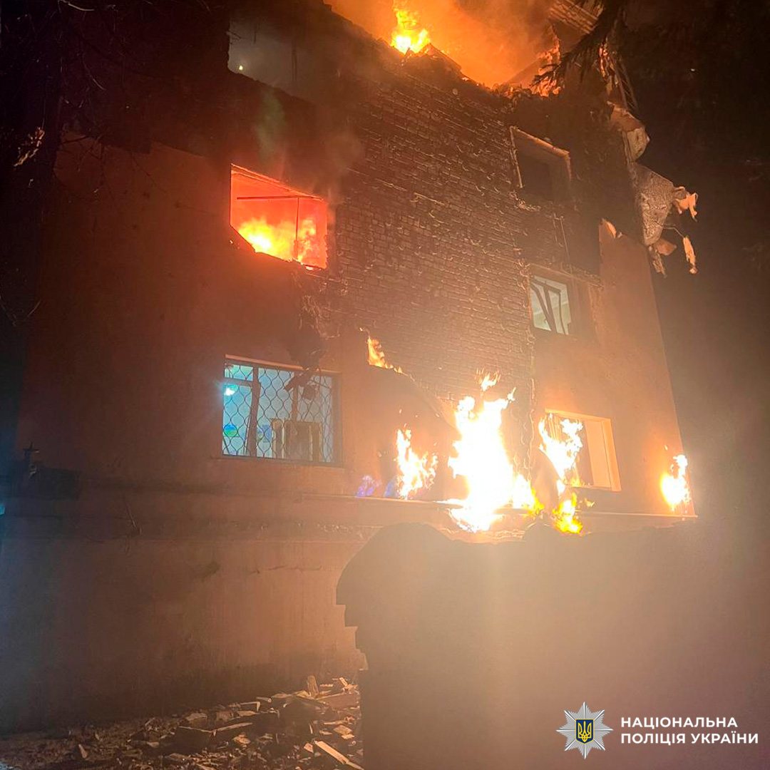 Багатоповерховий житловий будинок уночі, охоплений полум’ям.