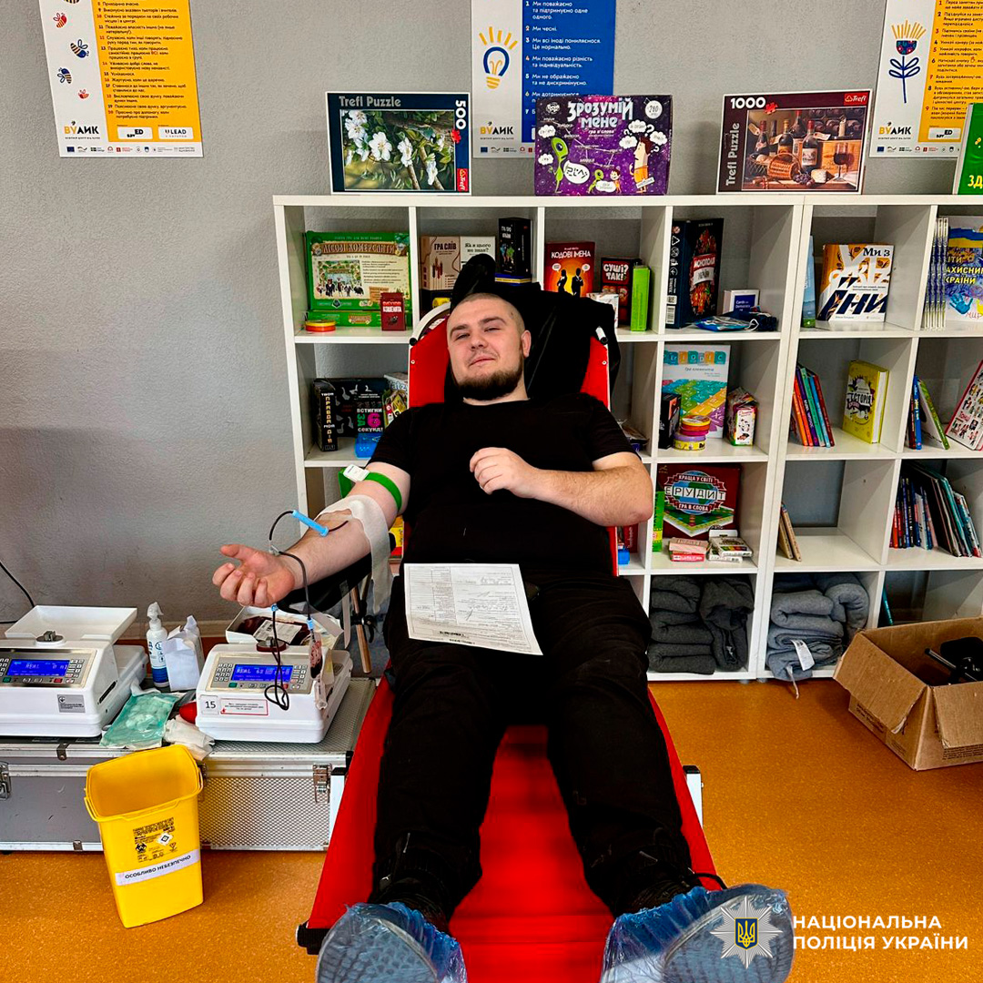 Поліцейський Харківщини, який здає кров у спеціальному кріслі, поруч видно медичне обладнання та контейнери.