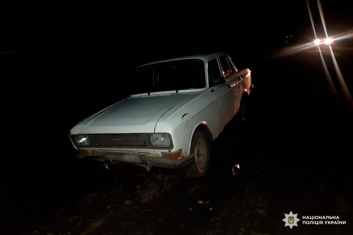 Старий білий автомобіль на темній ділянці вночі.