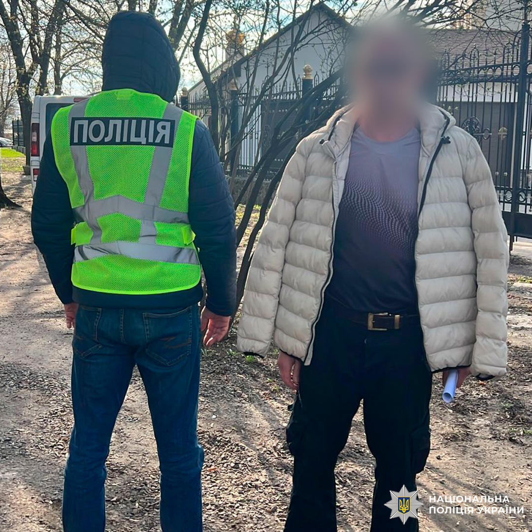 Працівник поліції у світловідбивному жилеті з затриманним чоловіком, який напав на військовослужбовця ТЦК під час заходів оповіщення.