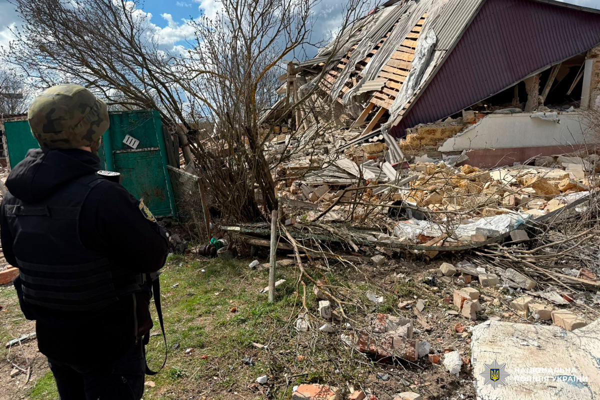 Поліцейський у захисному спорядженні оглядає зруйновану будівлю. Зафіксовано значні пошкодження стін та даху.