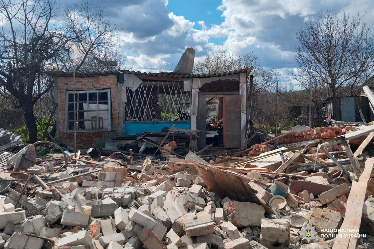Цегляна будівля з обваленим дахом і розбитими вікнами, навколо уламки та побутові речі.