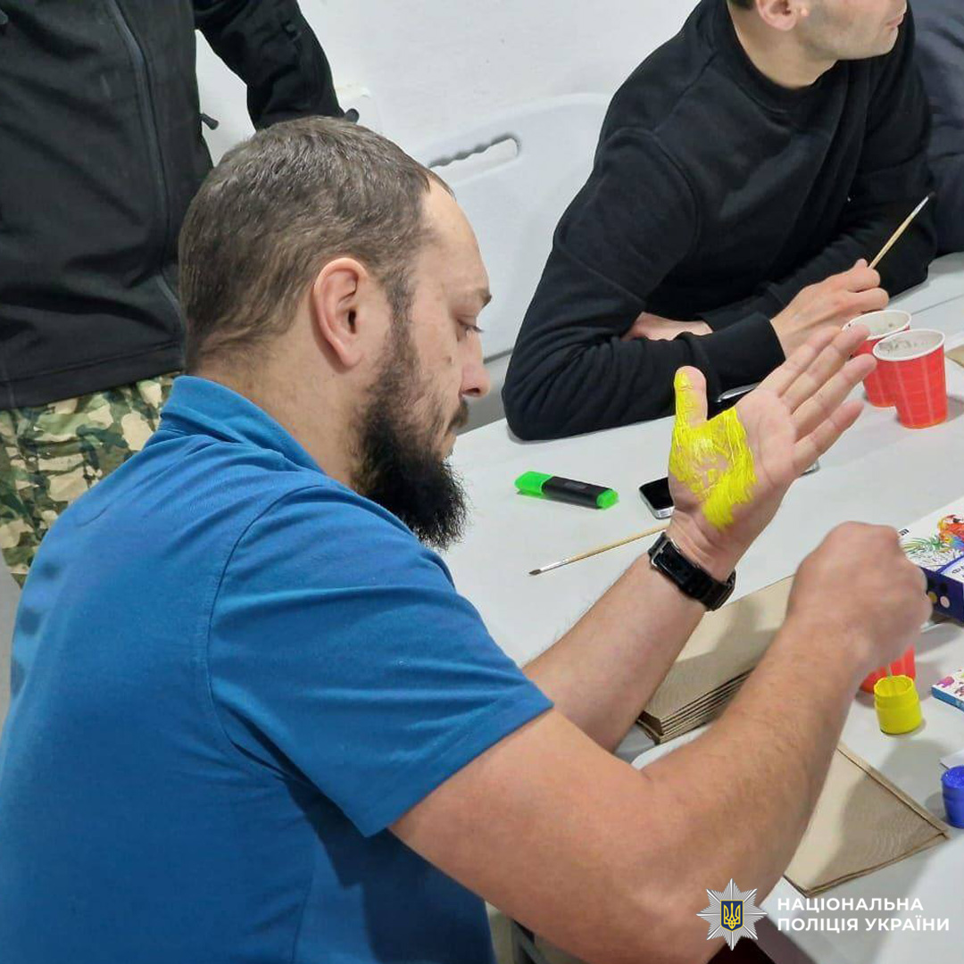 Учасник арт-активності наносить яскраву жовту фарбу на долоню під час творчого заходу.