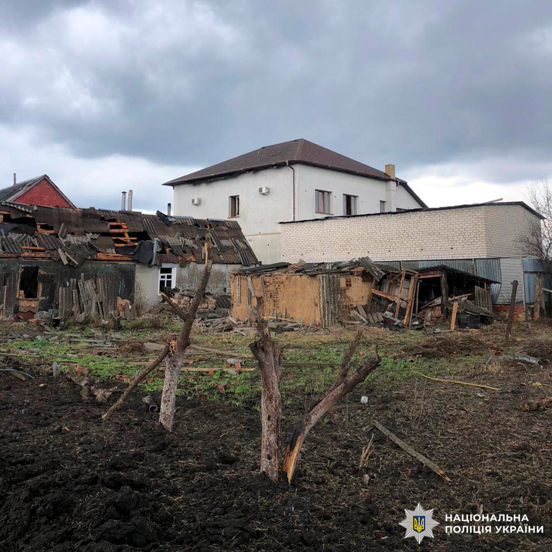 Пошкоджений житловий квартал із частково зруйнованими будівлями, уламками дерев та слідами руйнувань.