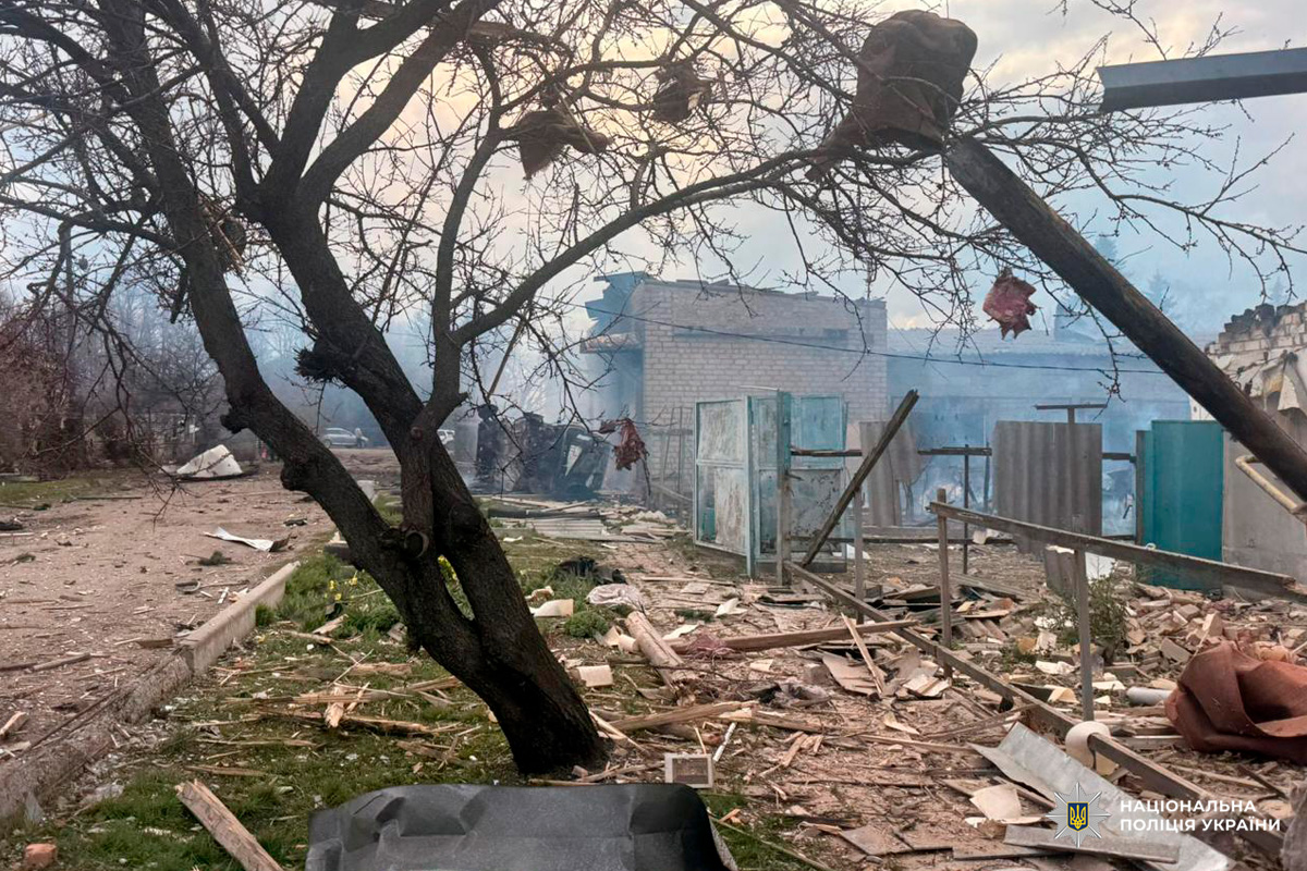 Зруйнована будівля та територія після вибуху: уламки дерева й металу, дим над пошкодженим приміщенням.