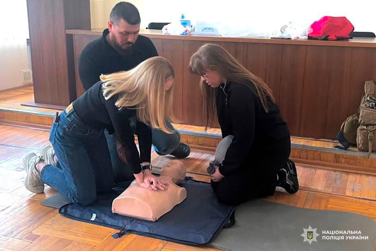 Поліцейські відпрацьовують навички серцево‑легеневої реанімації: компресії та штучне дихання на манекені під наглядом інструктора.