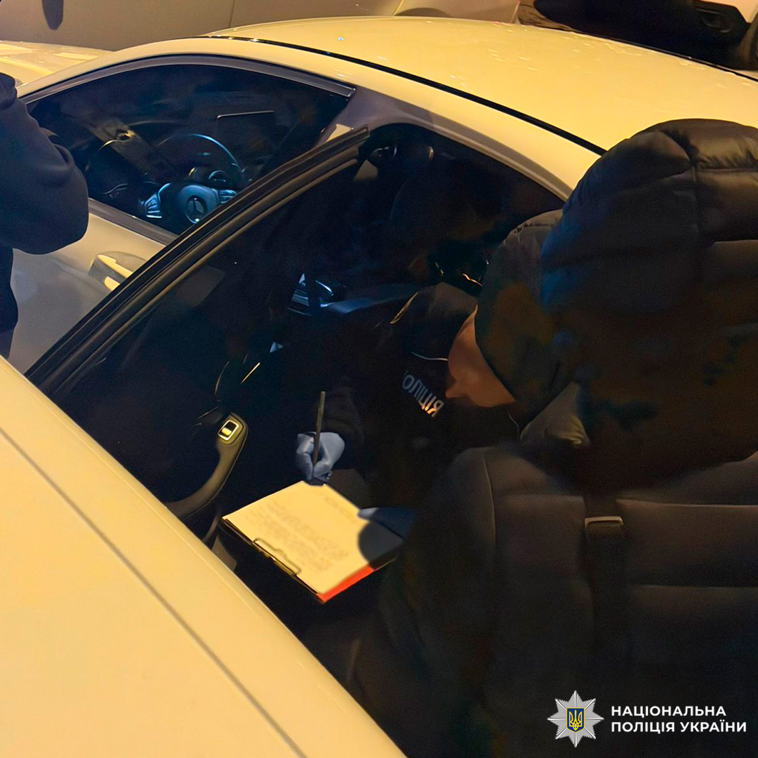 Поліцейський у службовому автомобілі заповнює протокол на планшеті, нічна робота документування.