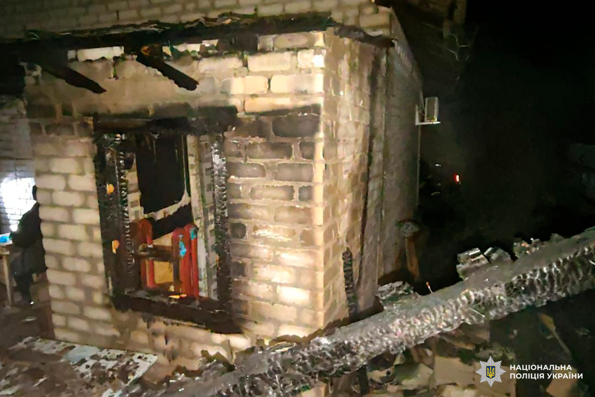 Цегляна будівля з ознаками пожежі: обгорілі ділянки навколо вікна та даху, зафіксовано наслідки займання.