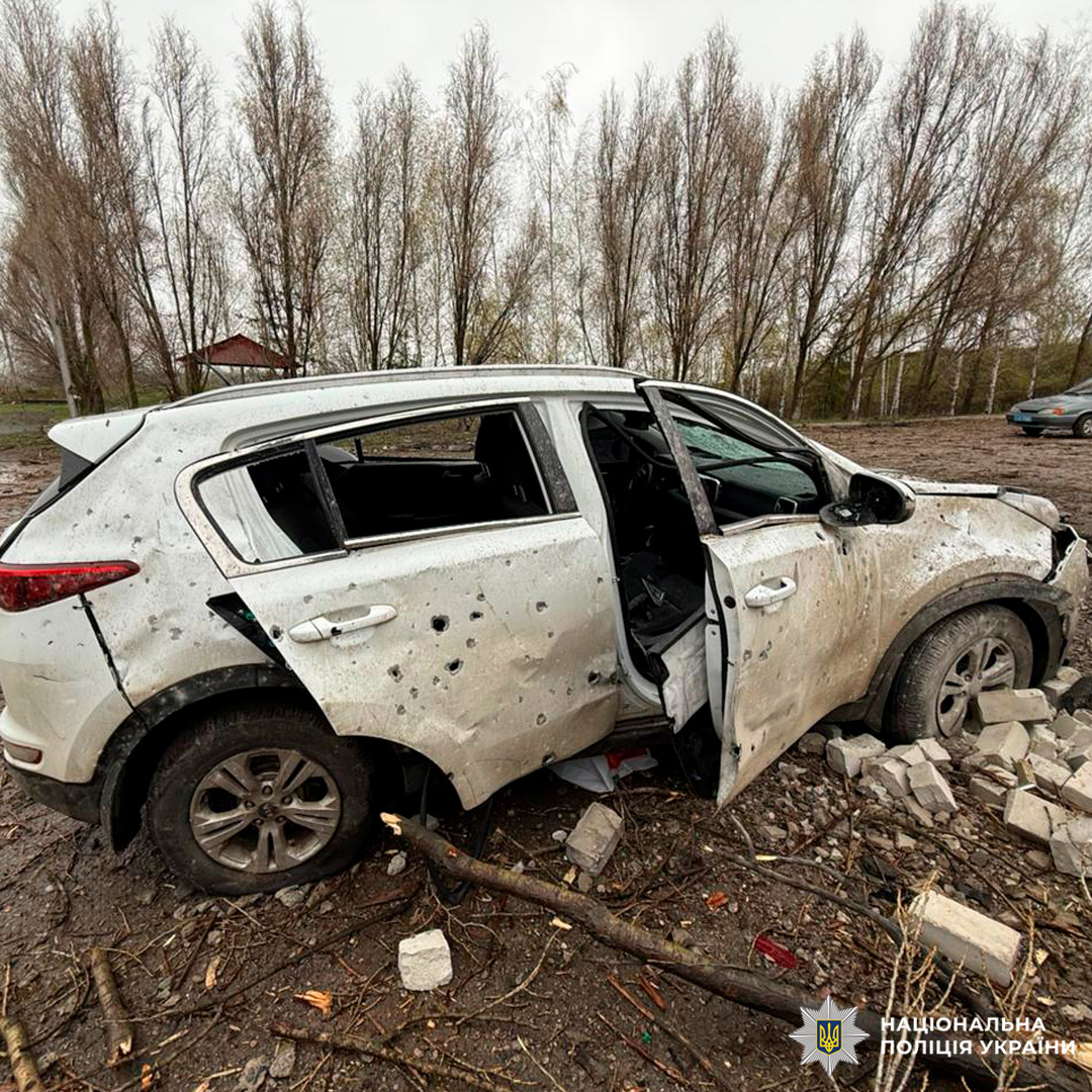 Білий позашляховик із численними пошкодженнями кузова та розбитими вікнами, зафіксований серед уламків і пошкодженої рослинності.