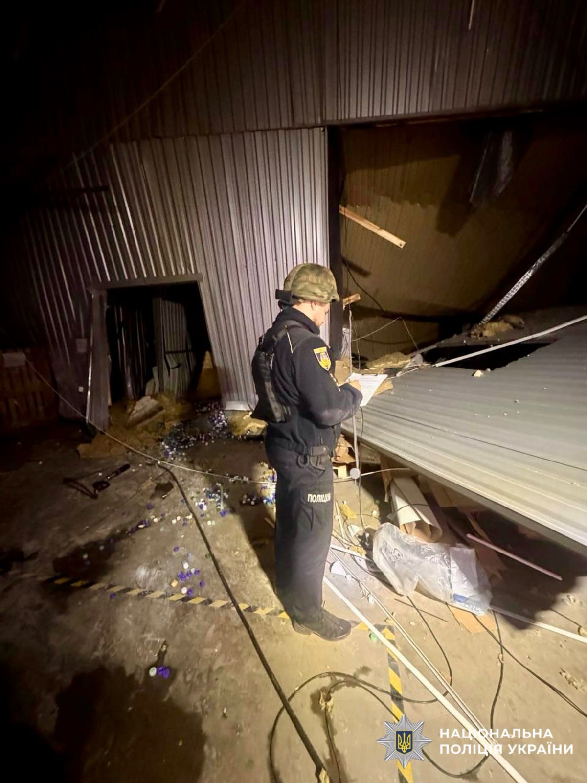 На фотографії зображено поліцейського, який фіксує наслідки атаки рф у області.