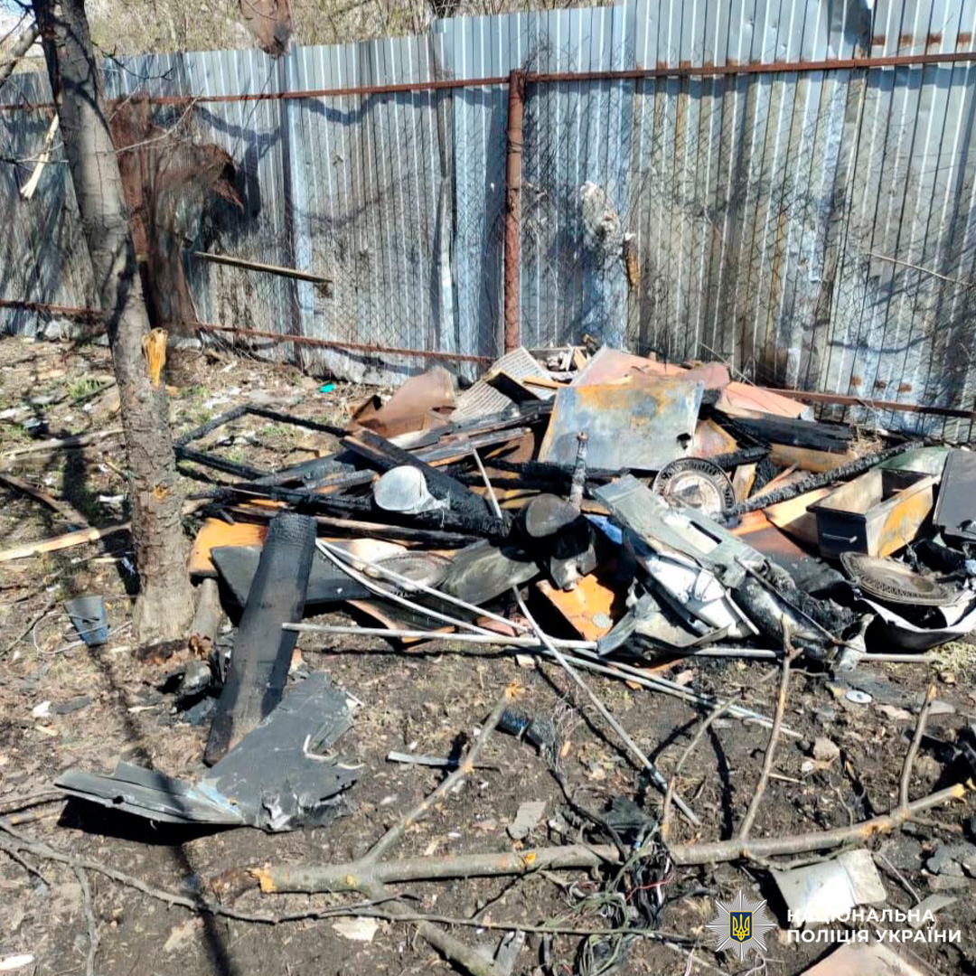 Обгорілі уламки металу біля паркану після вибуху.
