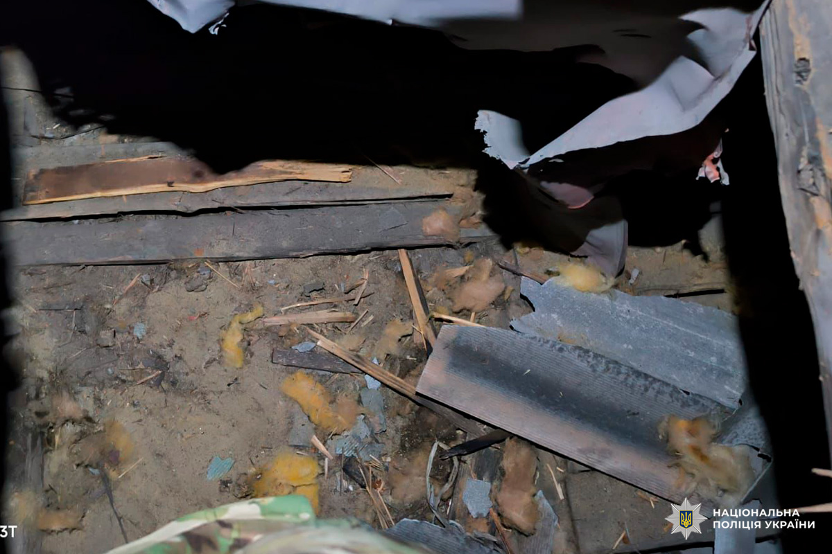 Зруйнована частина будівлі: уламки деревини, пошкоджені металеві листи та розкиданий утеплювач на ґрунті.