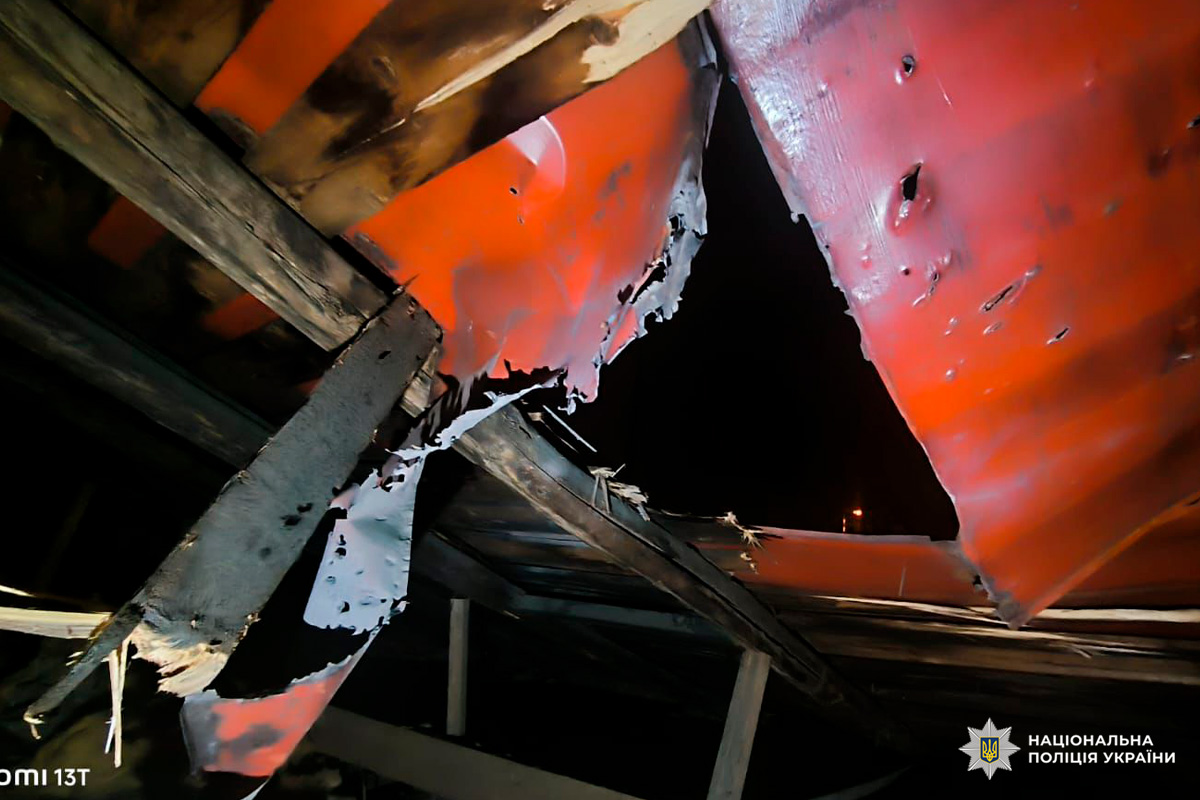 Пошкоджена покрівля: зігнуті металеві листи та зруйновані дерев’яні балки, крізь отвори видно нічне небо.