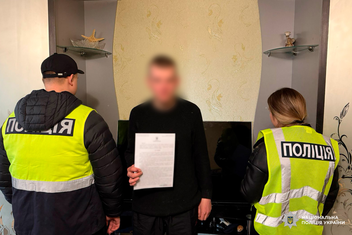 Двоє поліцейських у жилетах із написом “ПОЛІЦІЯ” поруч із особою, яка тримає документ.