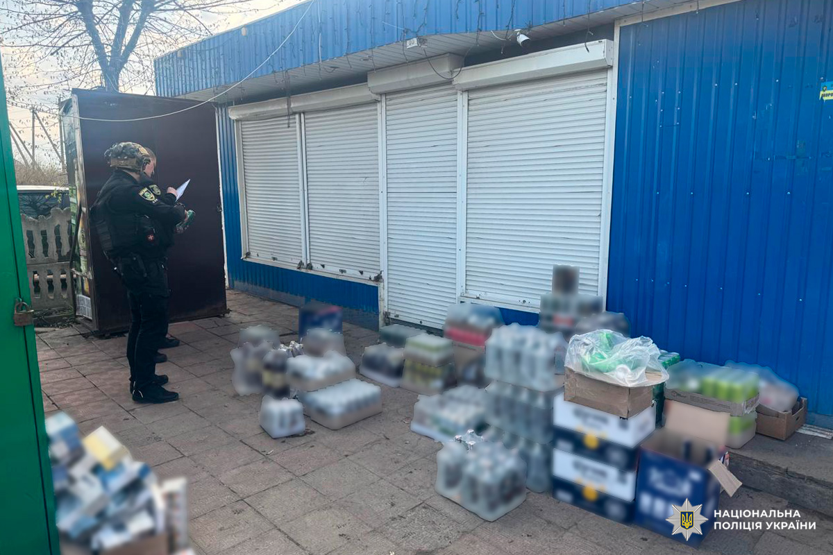 Поліцейський оглядає вилучені коробки та пакунки біля будівлі з ролетами.