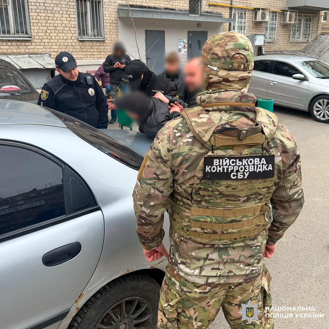 Співробітники СБУ та поліції проводять затримання біля автомобіля у міській зоні.