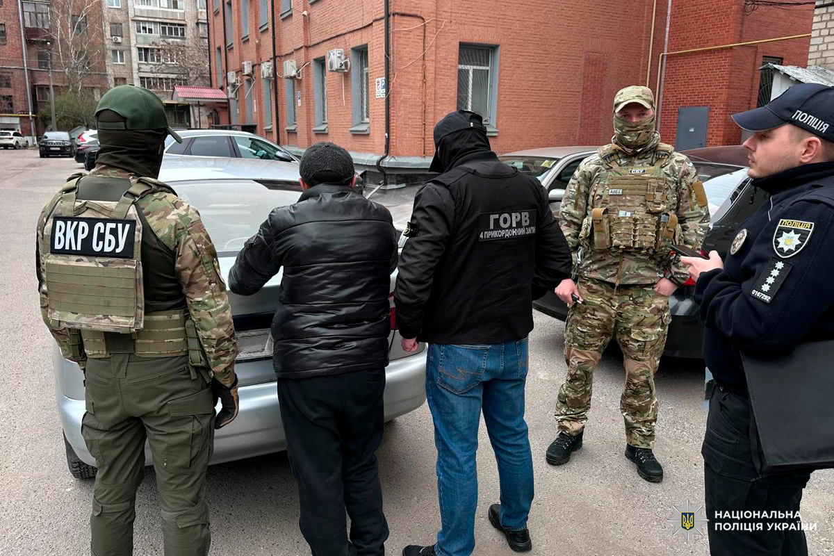 Правоохоронці проводять затримання біля автомобіля у міському середовищі.