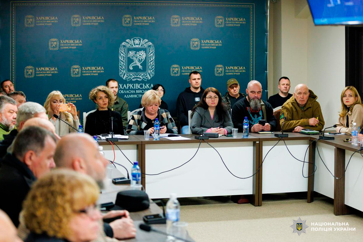 Офіційна нарада у Харківській обласній військовій адміністрації. Учасники сидять за столом із мікрофонами та документами.