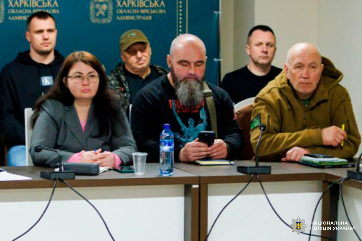 Офіційна нарада у Харківській обласній військовій адміністрації. Учасники сидять за столом із мікрофонами та документами.