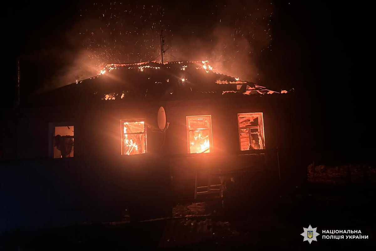 Будинок у Харківській області охоплений вогнем, пожежа поширюється через дах та вікна; на фасаді видно драбину та супутникову антену.