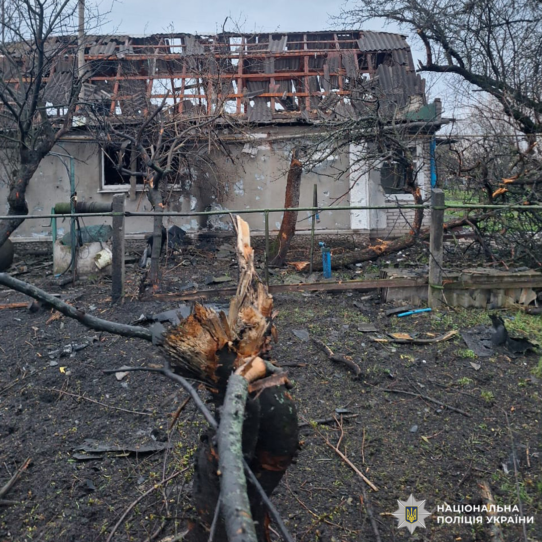 Пошкоджений житловий будинок із частково зруйнованим дахом та вибитими вікнами, поруч уламки дерев і зруйнована огорожа.