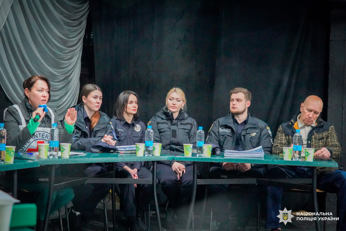 Поліцейські у формі беруть участь у робочій зустрічі, перед ними документи та вода.