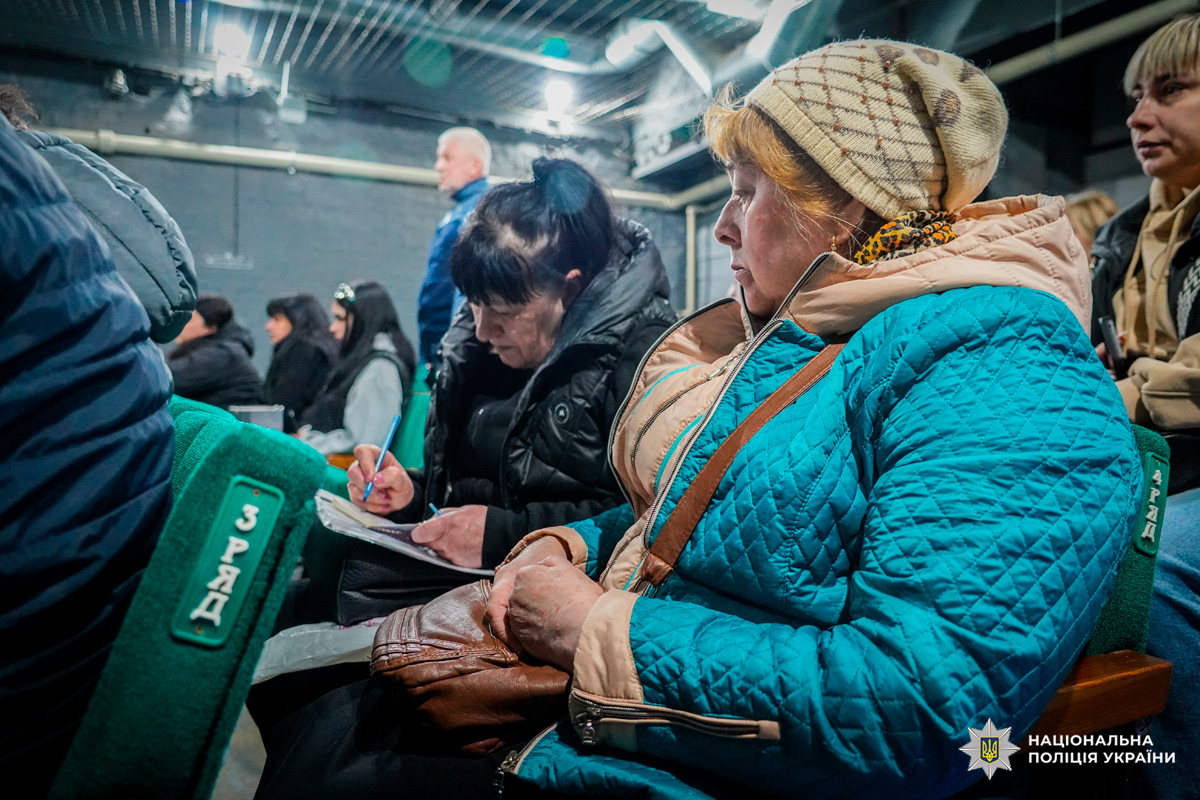 Учасники зустрічі сидять у залі в теплих куртках та роблять нотатки.