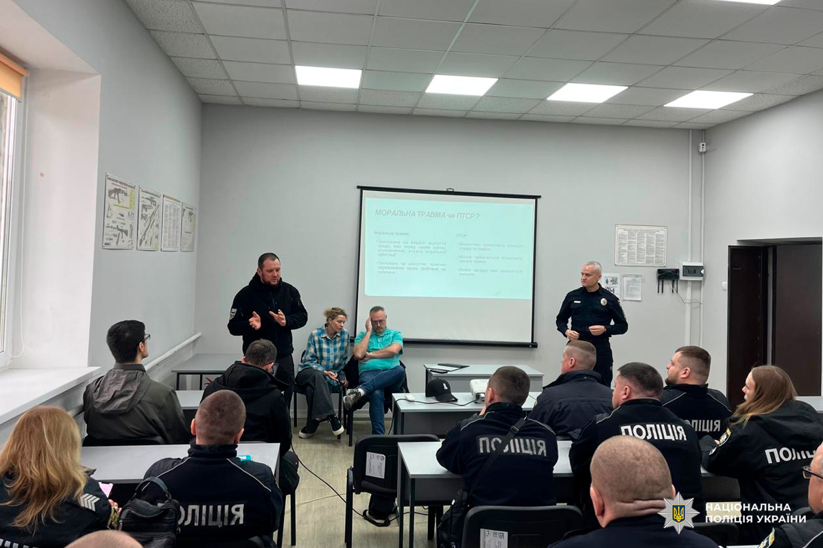 Поліцейські у формі слухають лекцію про моральну травму та ПТСР у навчальній аудиторії.