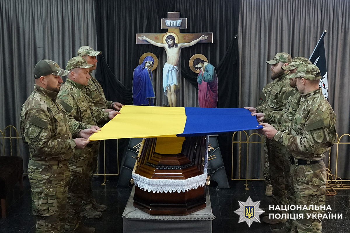 Бійці тримають прапор над труною