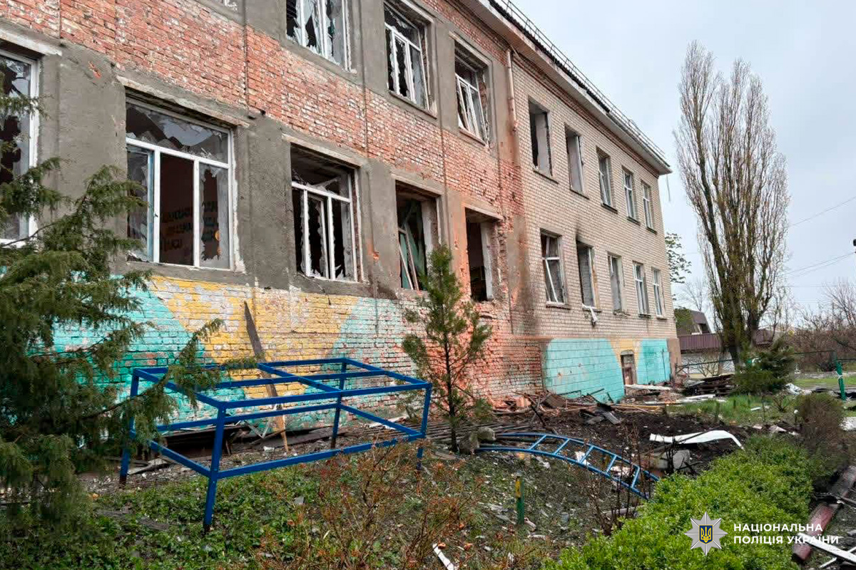 Цегляна будівля з вибитими вікнами та пошкодженим фасадом, уламки на землі.