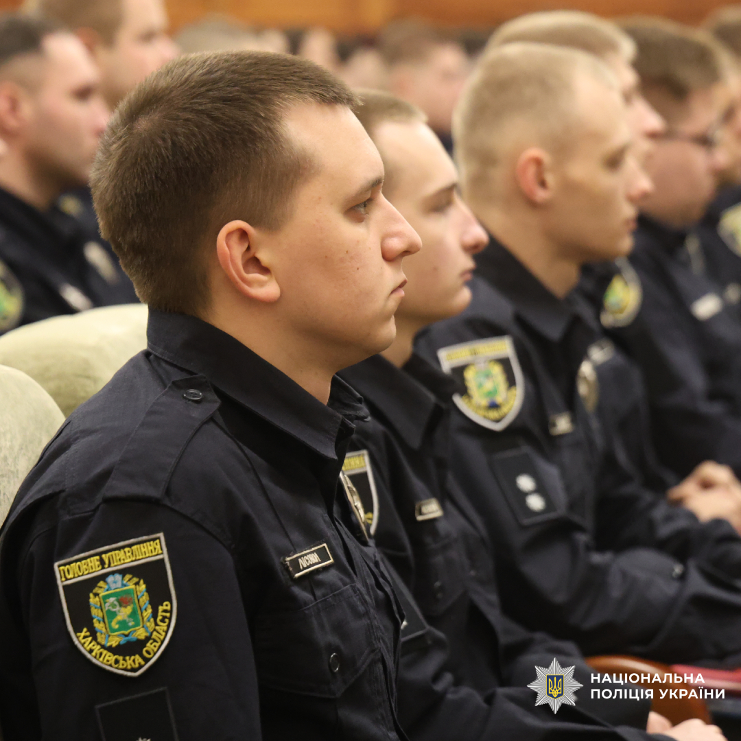 Група поліцейських у темно‑синій формі сидить рядами, ймовірно під час офіційного заходу або навчання.