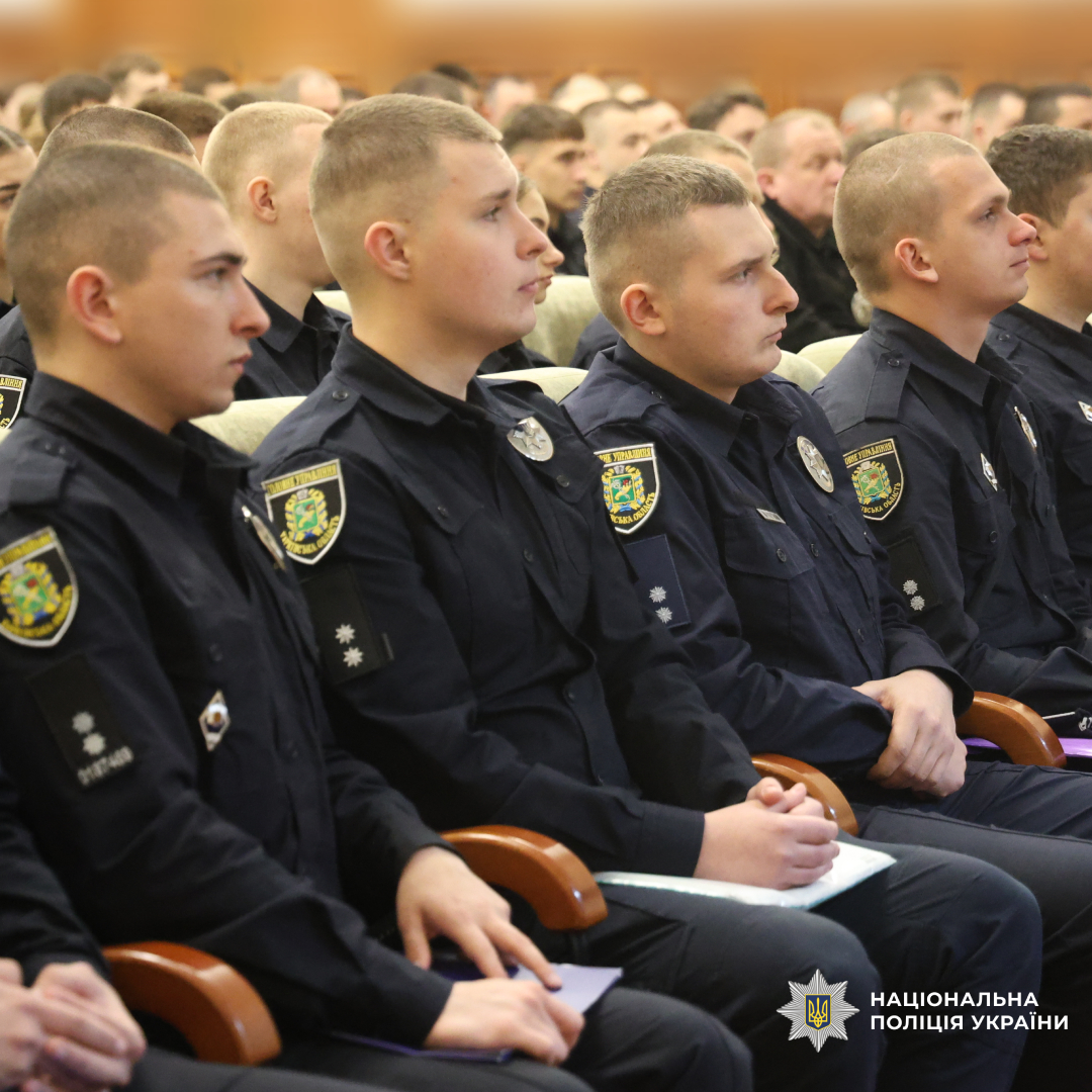 Група поліцейських у темно‑синій формі сидить рядами, ймовірно під час офіційного заходу або навчання.