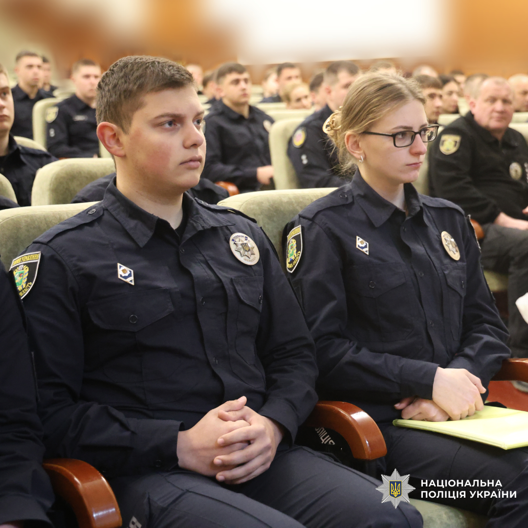 Група поліцейських у темно‑синій формі сидить рядами, ймовірно під час офіційного заходу або навчання.