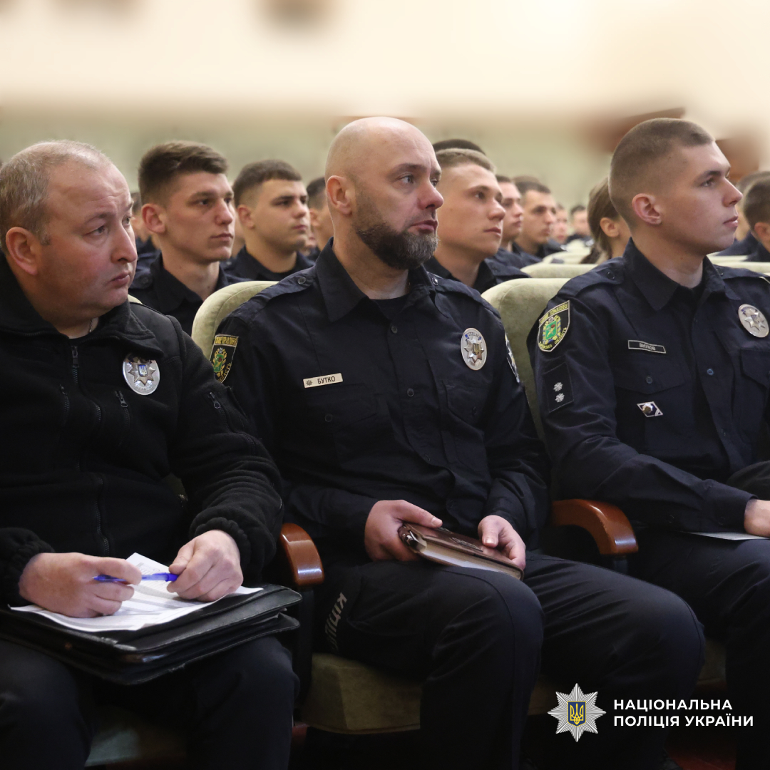 Група поліцейських у темно‑синій формі сидить рядами, ймовірно під час офіційного заходу або навчання.