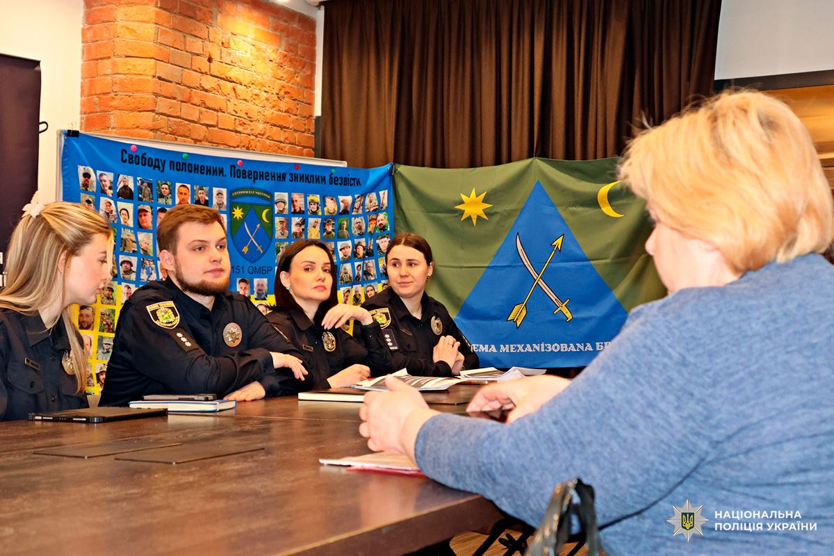 Поліцейські та представник громади під час робочої зустрічі на тлі банерів із закликами щодо полонених та символіки 151‑ї механізованої бригади.
