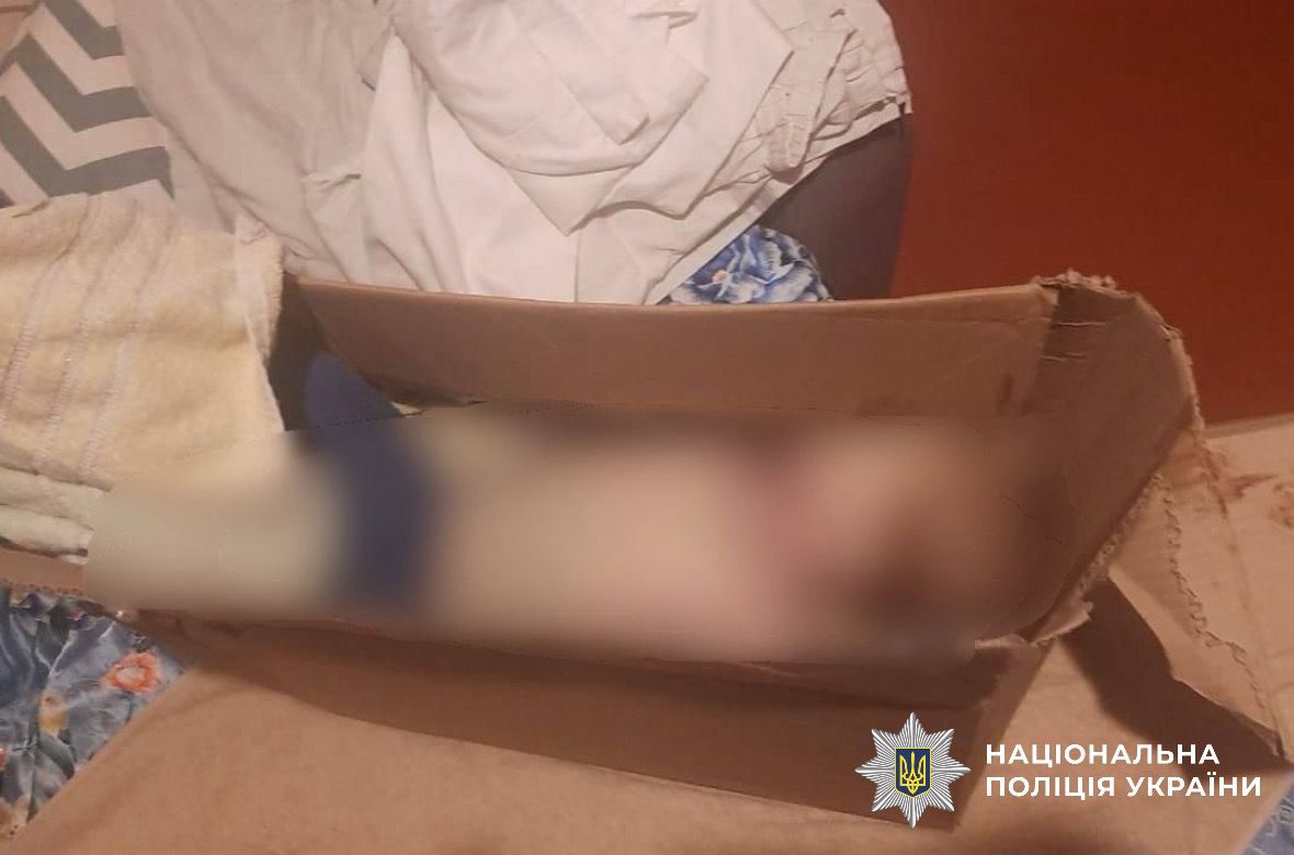 На фотографії зображено тіло дитини, яку виявили у коробці в шафі.