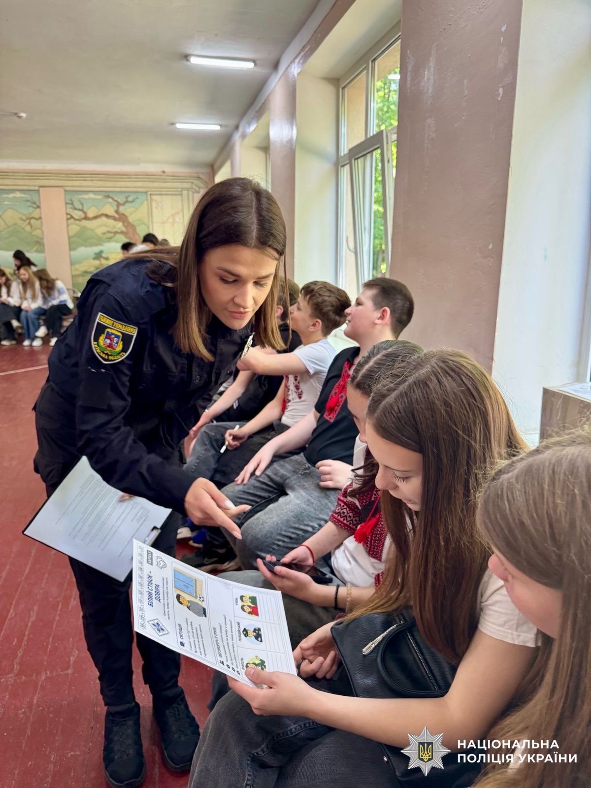 На фото зображена поліцейська яка розповідає дітям про день вишиванки