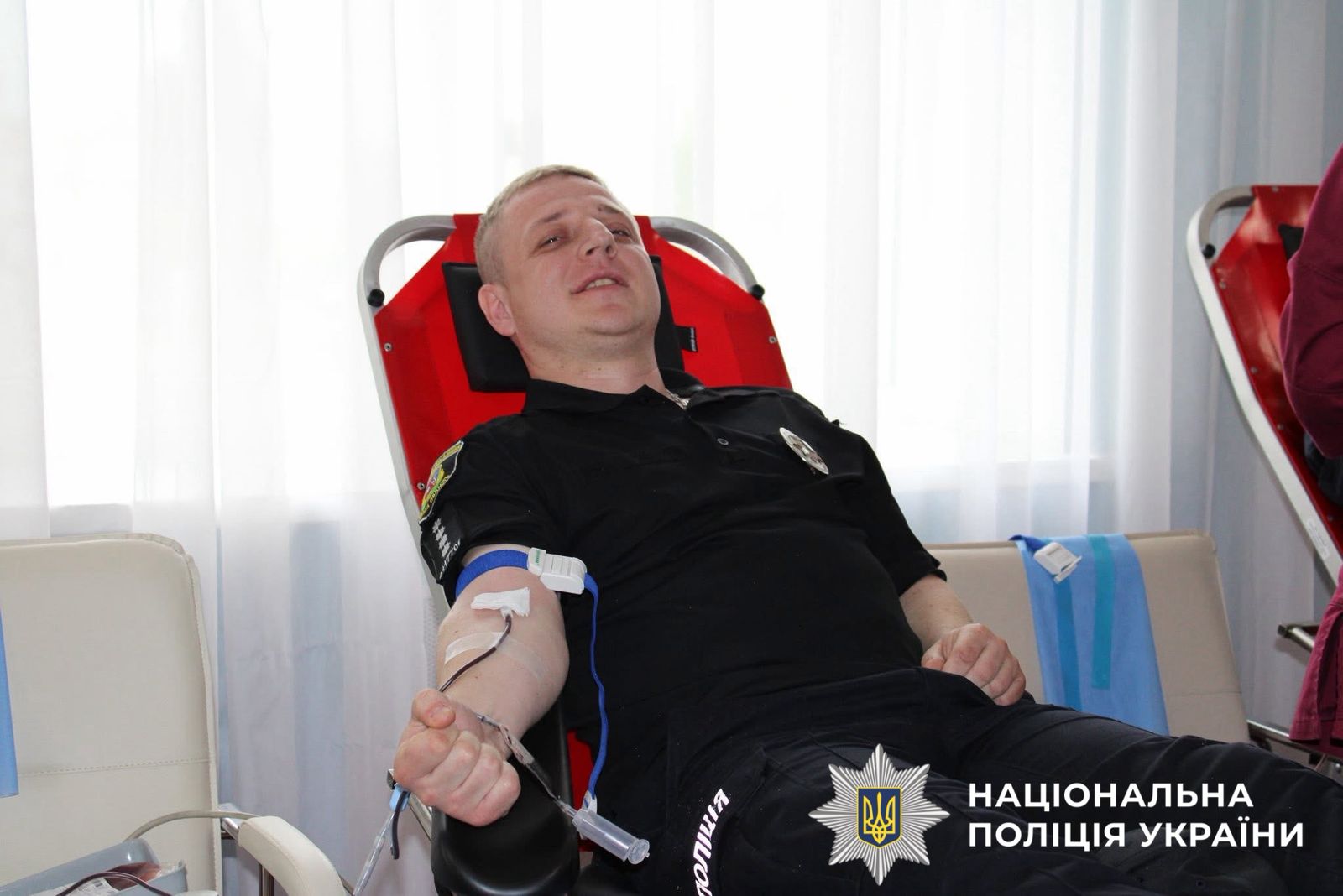 На фото зображено як поліцейський здає кров.