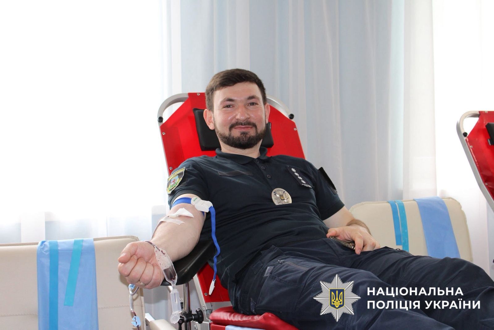 На фото зображено як поліцейський здає кров.