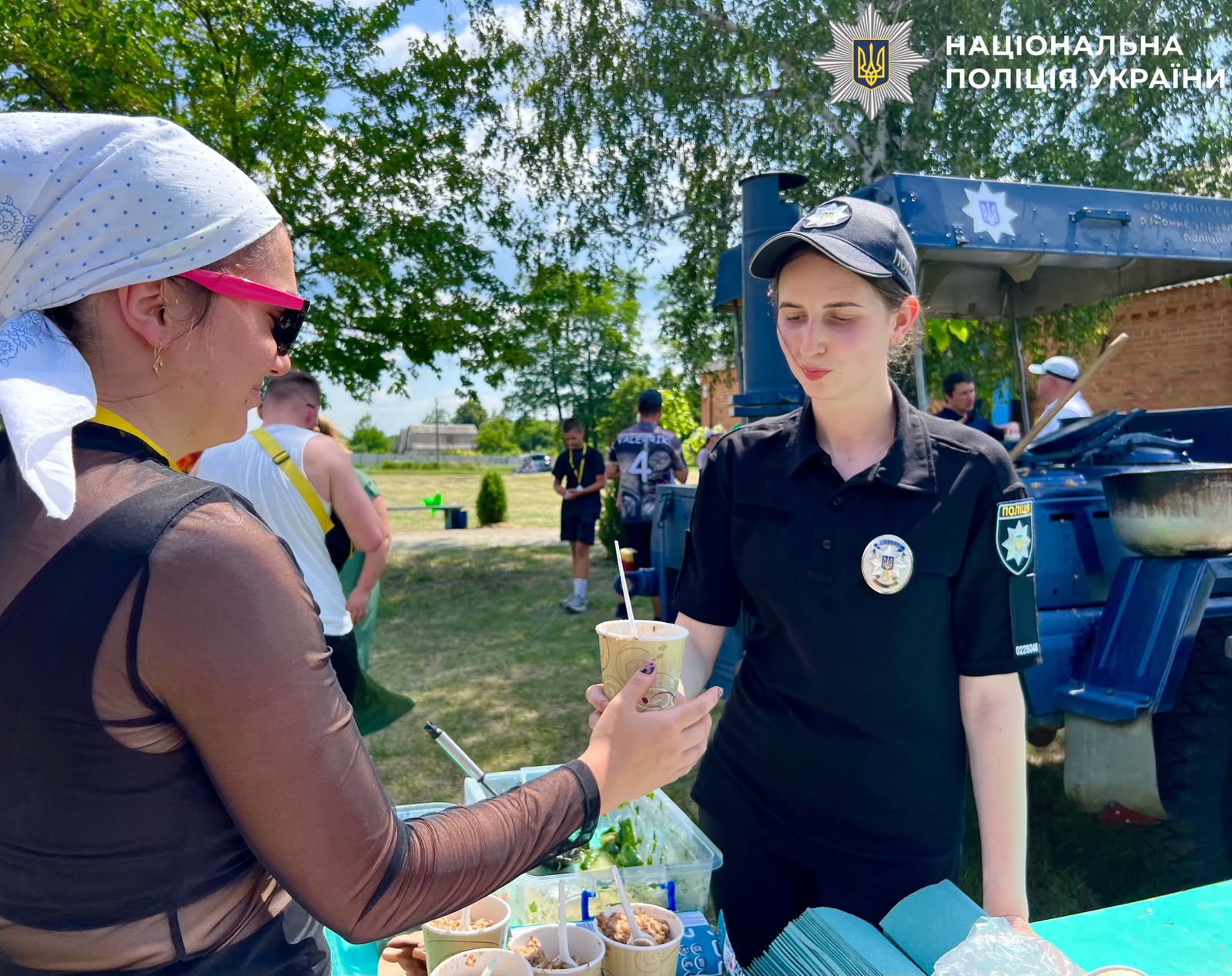На фотографії зображено поліцейських Київщини, які долучилися до спортивного фестивалю та пригостили учасників поліцейською польовою кашею.