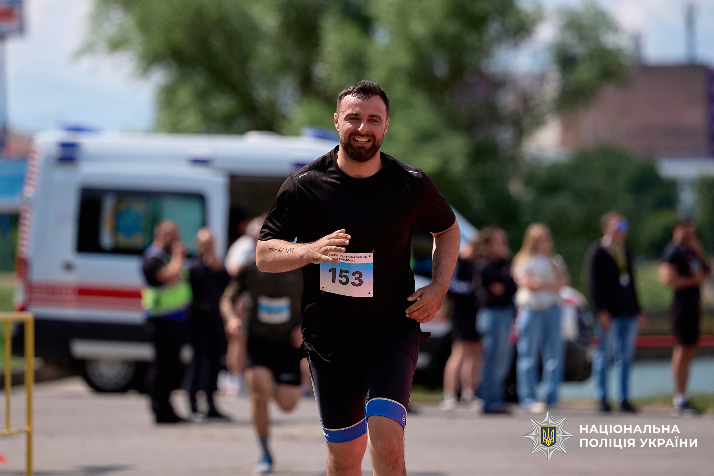 Учасник змагань у чорній футболці біжить і посміхається