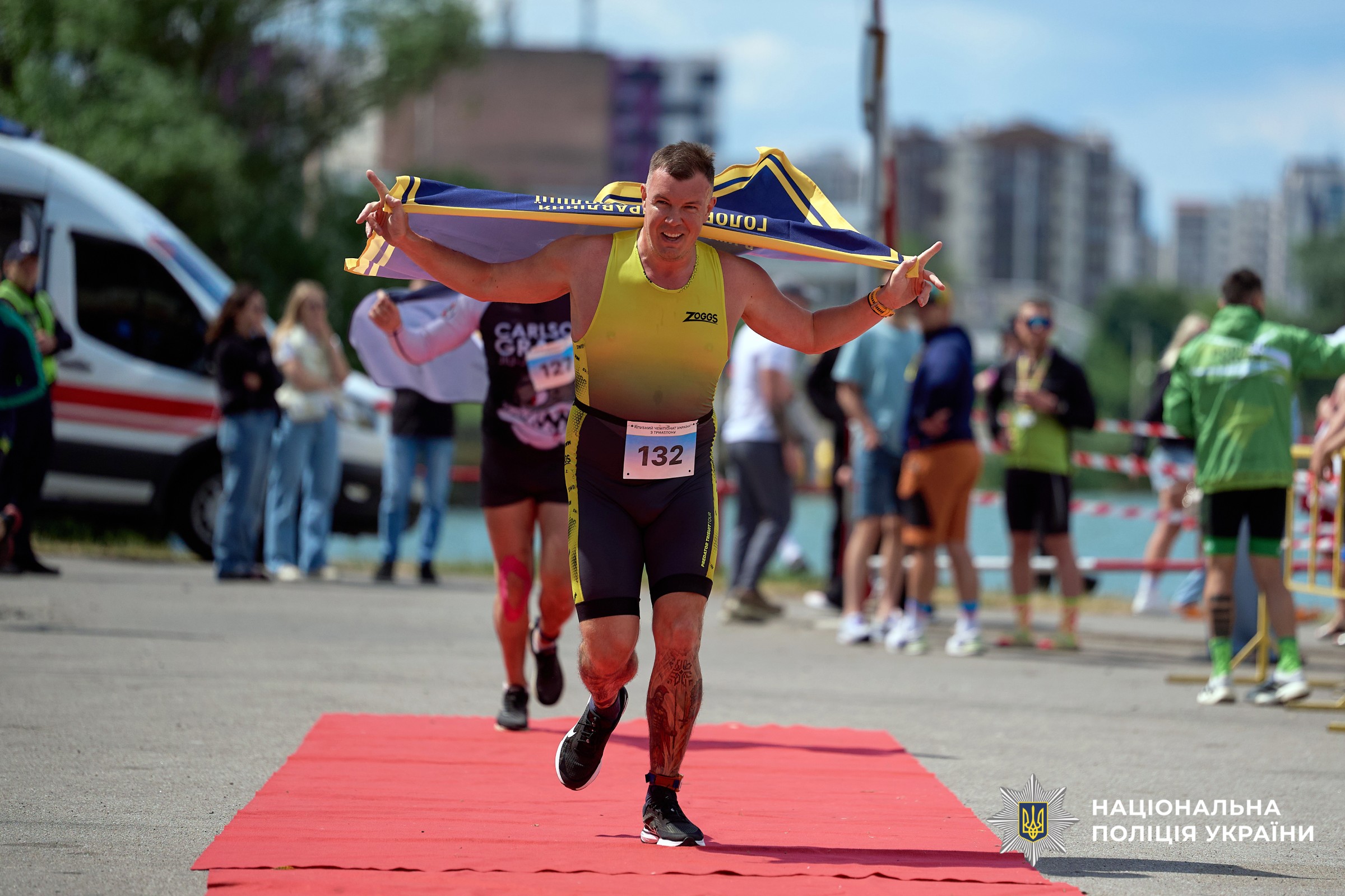 Учасник команди, заступник начальника ГУНП в Хмельницькій області Андрій Репчонок долає фінішну лінію з прапором ГУНП за спиною