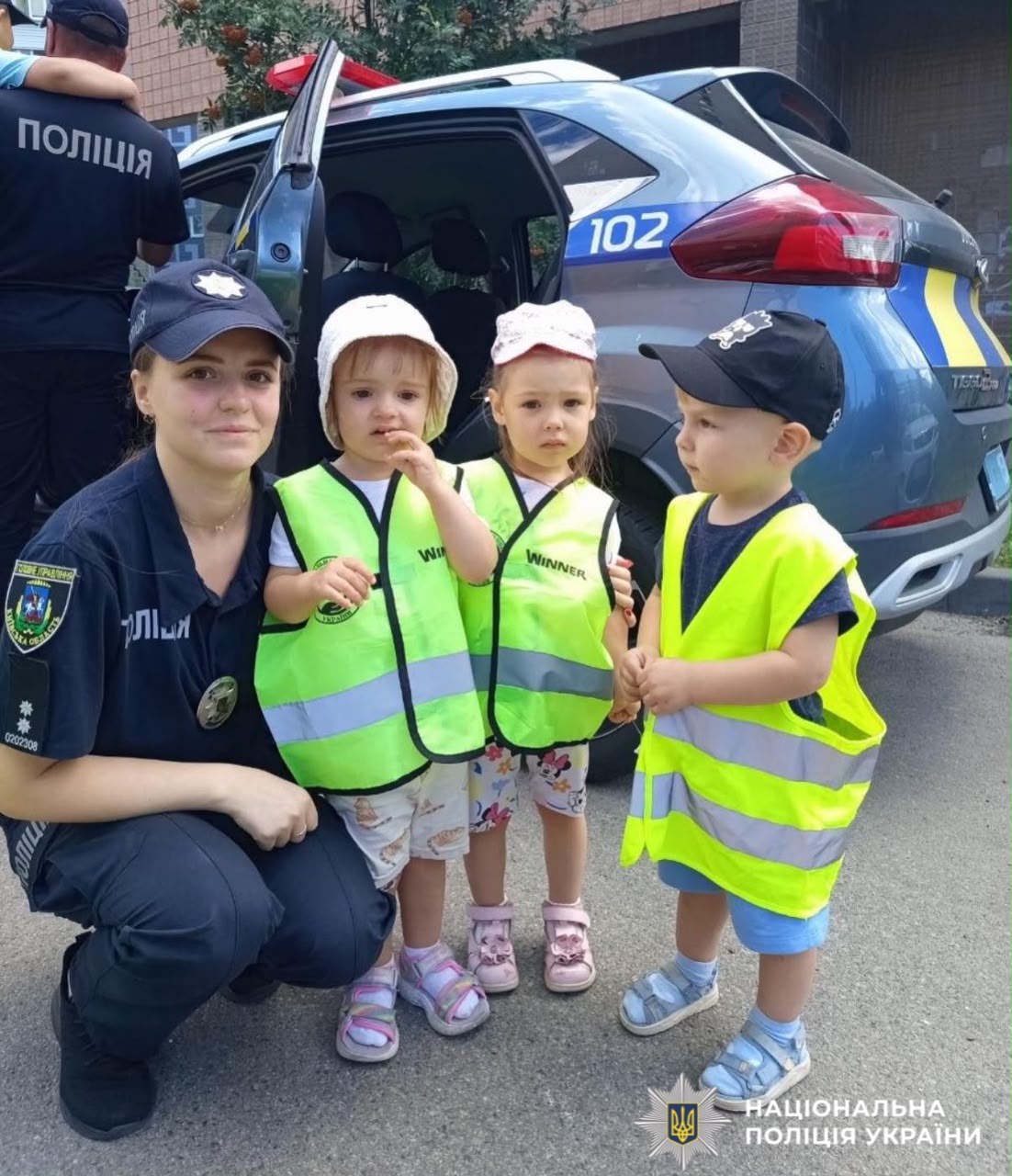 На фото діти та інспекторка ювенальної превенціії біля службового автомобіля.