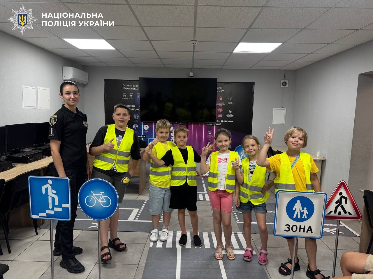 На фотографії зображено інспекторів Служби освітньої безпеки Броварського районного управління поліції, які провели для дітей пізнавальні зустрічі, присвячені правилам поведінки на дорозі.