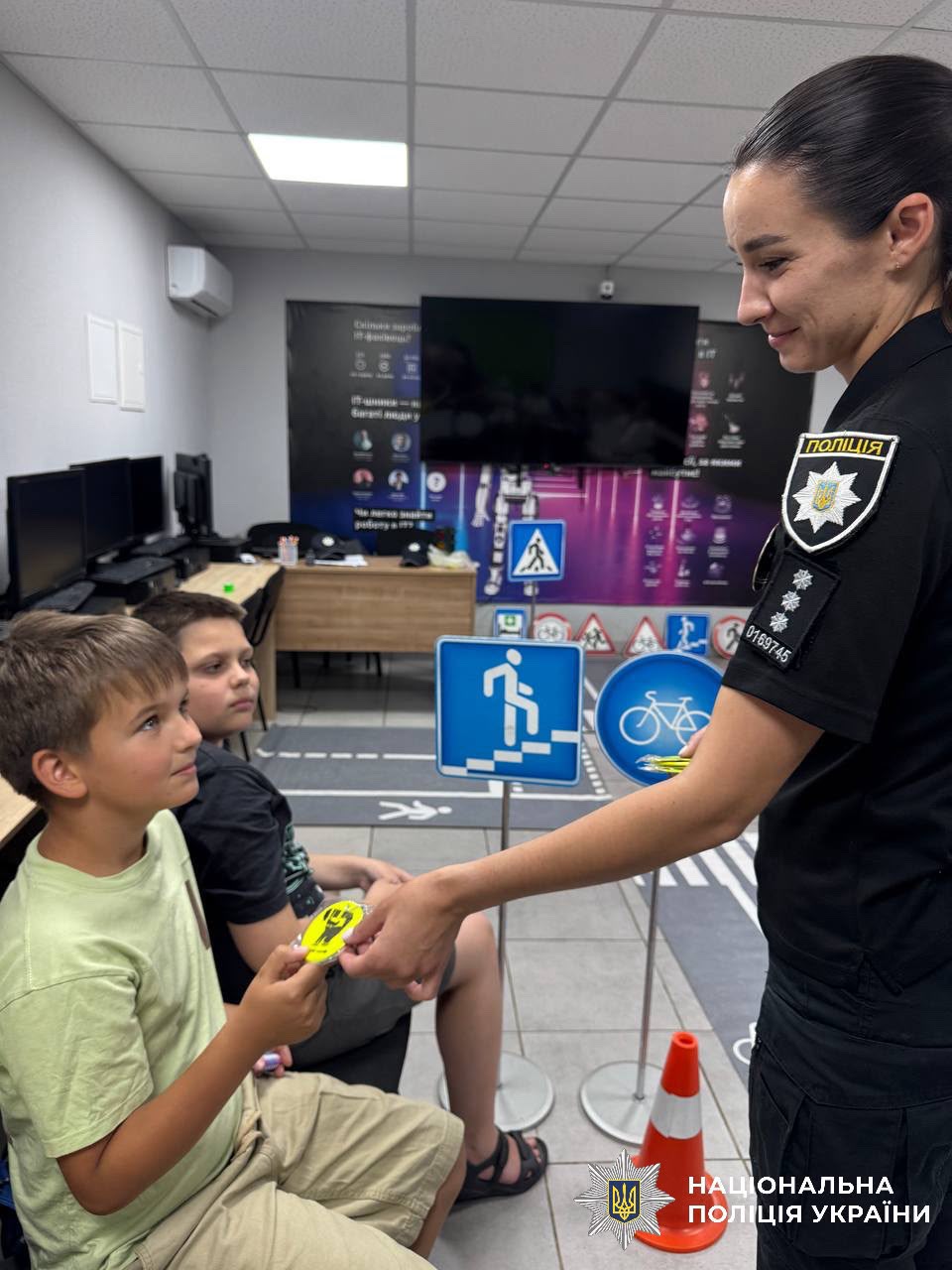 На фотографії зображено інспекторку Служби освітньої безпеки Броварського районного управління поліції, яка провела для дітей пізнавальні зустрічі, присвячені правилам поведінки на дорозі.