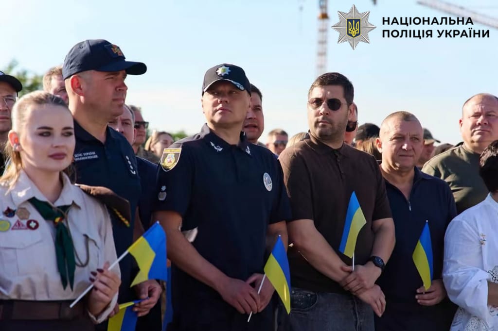 На фотографії зображено поліцейські Київщини, які спільно з громадою взяли участь у піднятті синьо-жовтого стягу на перехресті Бучі та Ворзеля.