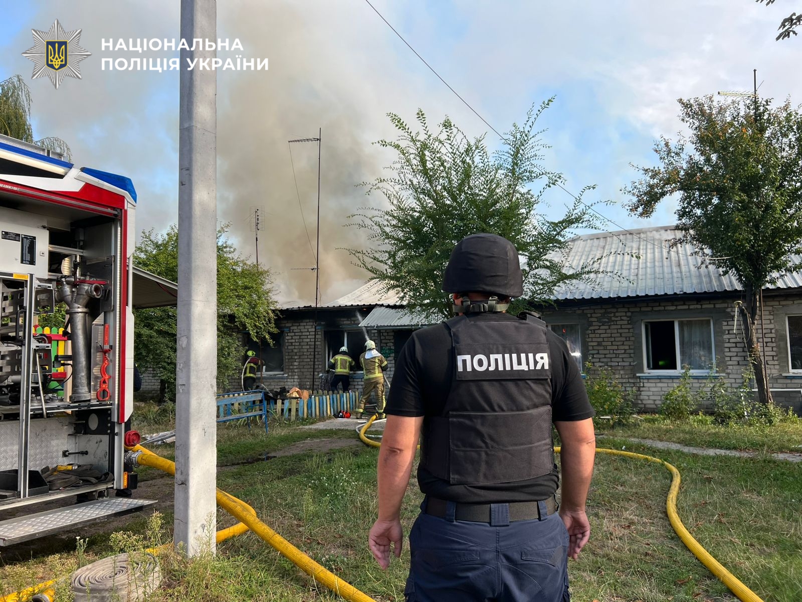 На фото правоохоронець на фоні наслідків атаки рф.
